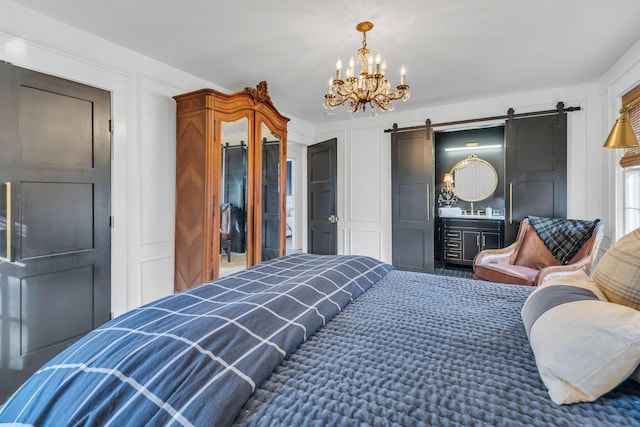 bedroom with a barn door, a chandelier, and ensuite bath