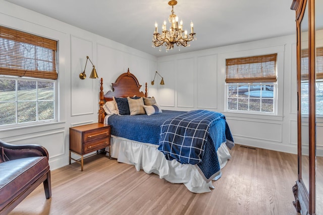 bedroom featuring multiple windows, a chandelier, and light hardwood / wood-style flooring