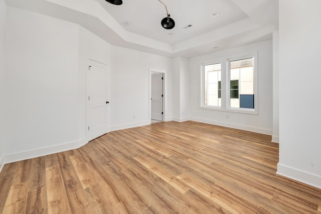 unfurnished room with a raised ceiling and light wood-type flooring