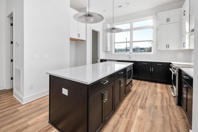 kitchen featuring stainless steel appliances, a kitchen island, white cabinets, and light hardwood / wood-style flooring