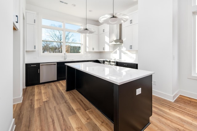 kitchen featuring wall chimney exhaust hood, sink, a center island, dishwasher, and light hardwood / wood-style floors