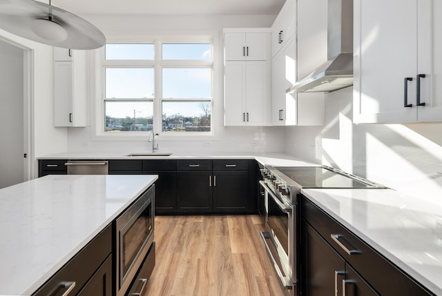 kitchen with stainless steel appliances, sink, white cabinets, and wall chimney exhaust hood