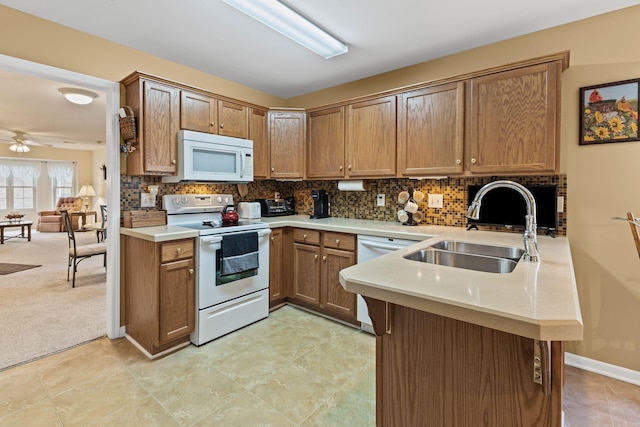 kitchen featuring sink, white appliances, kitchen peninsula, light colored carpet, and backsplash