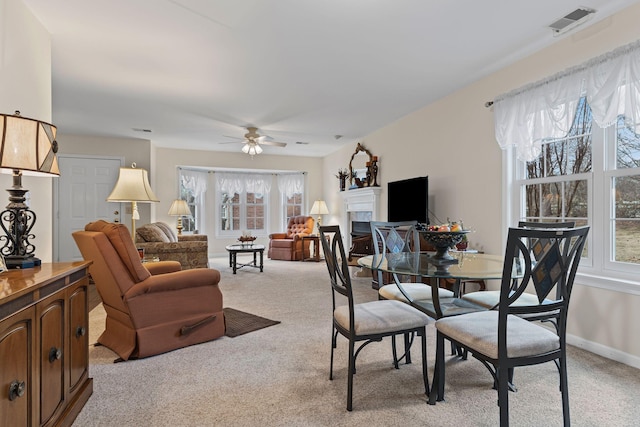 dining room with a healthy amount of sunlight, light colored carpet, and ceiling fan