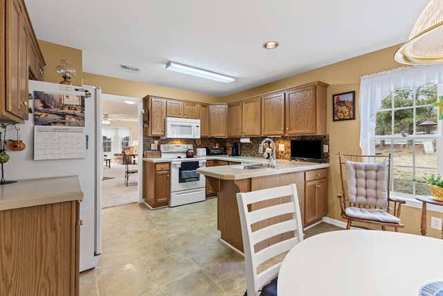 kitchen featuring plenty of natural light, sink, white appliances, and kitchen peninsula