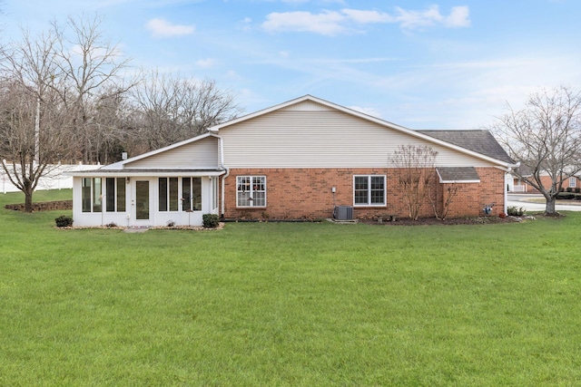 rear view of house with a yard, central AC unit, and a sunroom