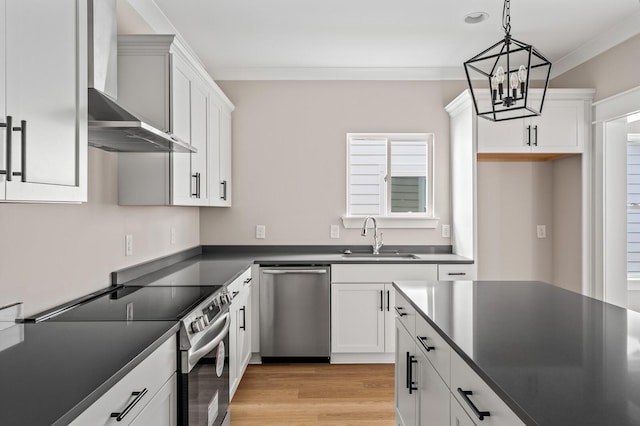 kitchen featuring sink, wall chimney range hood, pendant lighting, stainless steel appliances, and white cabinets