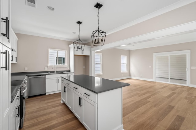 kitchen featuring hanging light fixtures, a center island, white cabinets, and appliances with stainless steel finishes