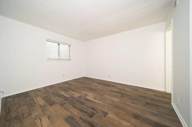 empty room with dark hardwood / wood-style floors and a textured ceiling