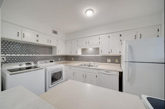 kitchen featuring sink, white cabinets, backsplash, washing machine and clothes dryer, and white appliances