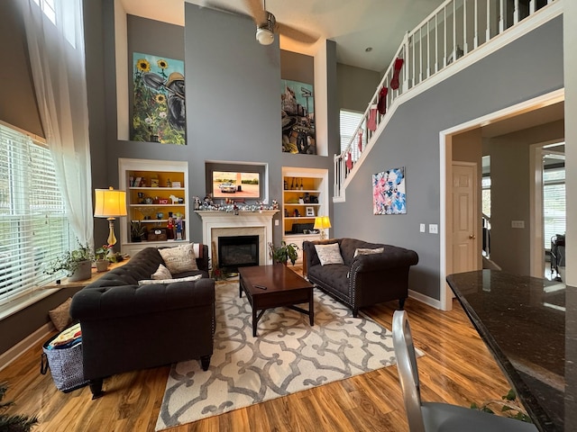 living room featuring hardwood / wood-style flooring, a towering ceiling, and built in features