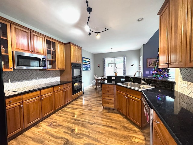 kitchen with sink, appliances with stainless steel finishes, backsplash, light hardwood / wood-style floors, and decorative light fixtures