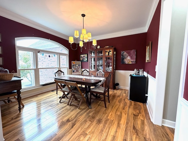 dining area with hardwood / wood-style flooring, ornamental molding, and a chandelier