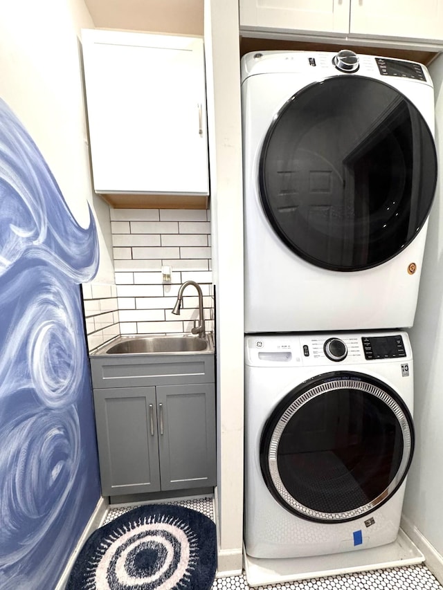 washroom with cabinets, stacked washer and dryer, tile patterned flooring, and sink