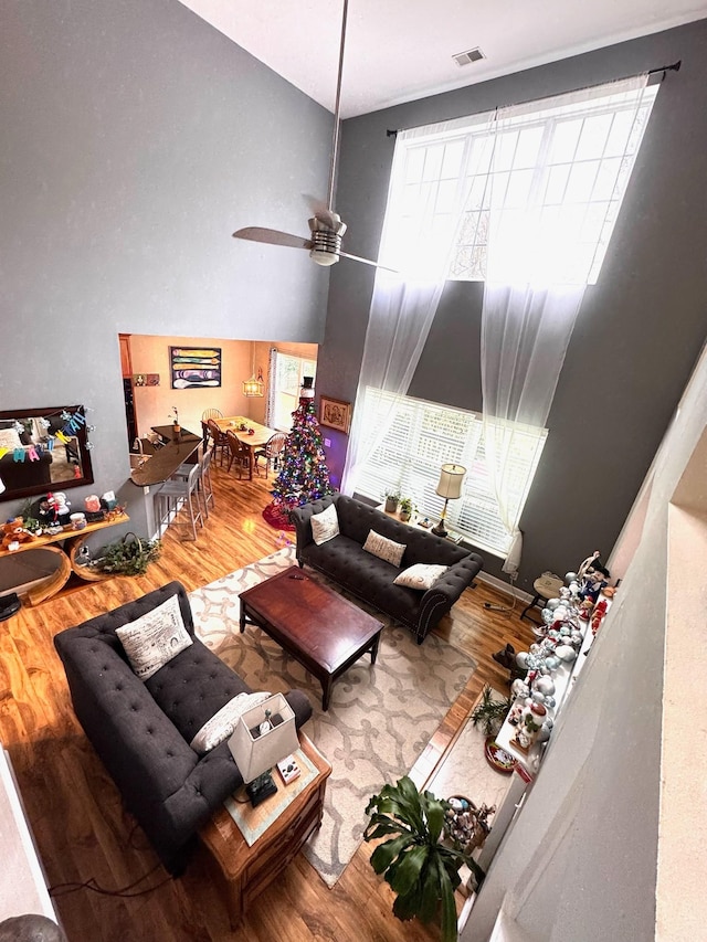 living room featuring a high ceiling, wood-type flooring, and ceiling fan