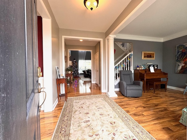 entryway featuring decorative columns, ornamental molding, and hardwood / wood-style flooring