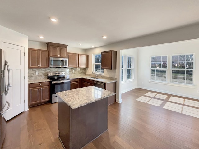 kitchen featuring dark wood-type flooring, sink, appliances with stainless steel finishes, a kitchen island, and backsplash