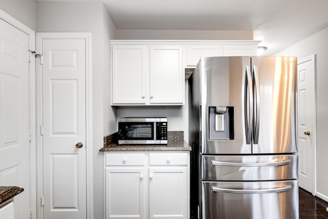 kitchen featuring dark stone countertops, appliances with stainless steel finishes, dark hardwood / wood-style flooring, and white cabinets