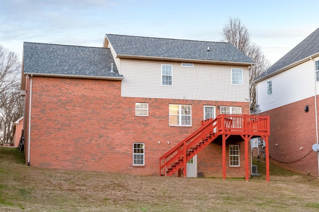 rear view of property featuring central AC unit, a lawn, and a deck