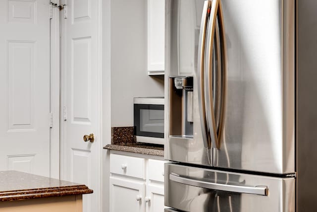 kitchen featuring white cabinetry, appliances with stainless steel finishes, and dark stone counters