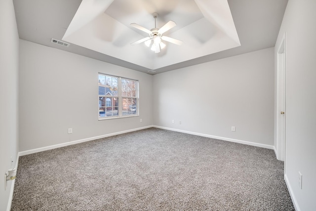 unfurnished room featuring ceiling fan, a tray ceiling, and carpet floors