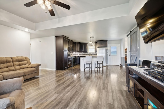 living room featuring hardwood / wood-style flooring, ceiling fan, beverage cooler, and a barn door