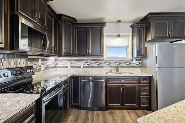 kitchen featuring sink, appliances with stainless steel finishes, light stone counters, dark hardwood / wood-style flooring, and decorative light fixtures