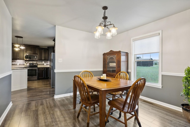 dining space with an inviting chandelier and dark hardwood / wood-style floors