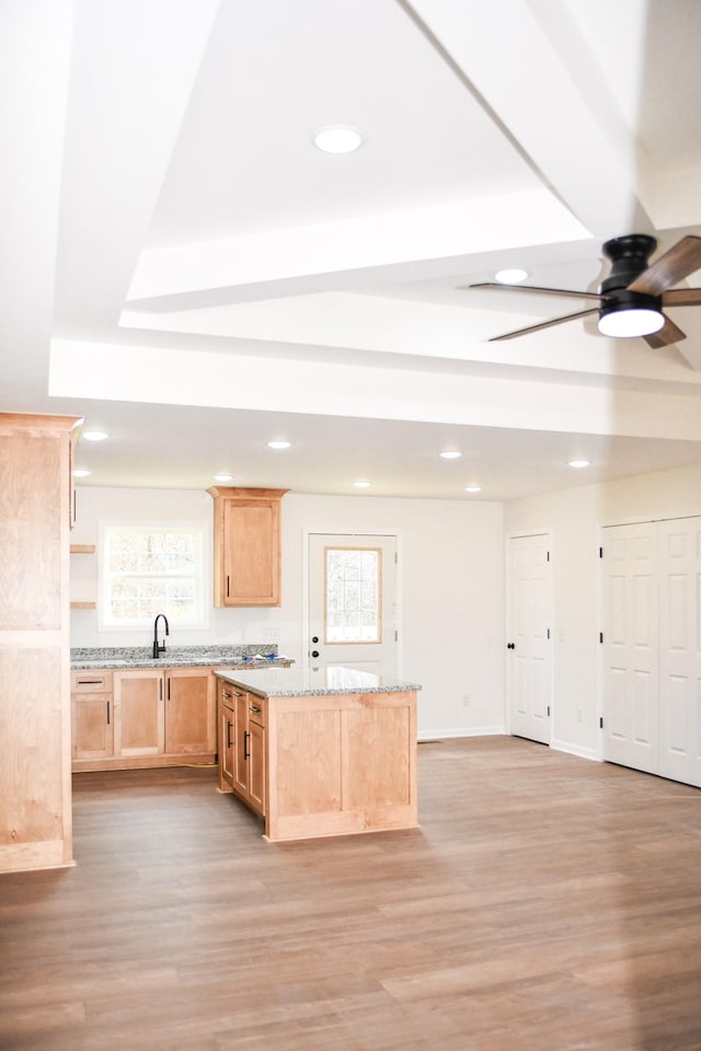 kitchen featuring light stone countertops, light brown cabinets, ceiling fan, and light hardwood / wood-style flooring