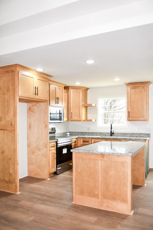 kitchen with stainless steel appliances, light stone countertops, a kitchen island, and light brown cabinets