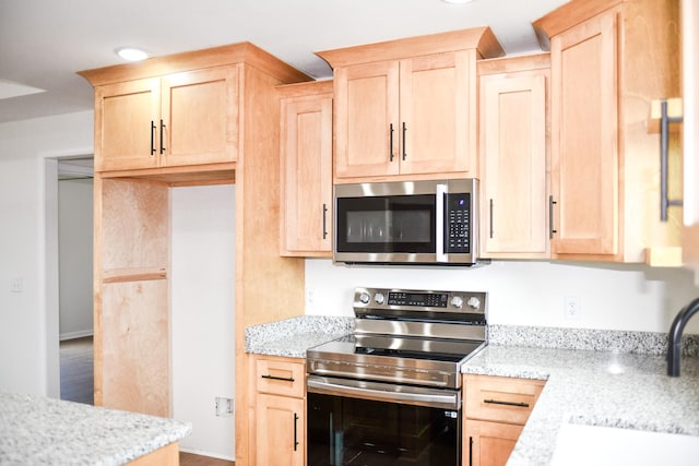 kitchen with stainless steel appliances, light stone countertops, sink, and light brown cabinetry