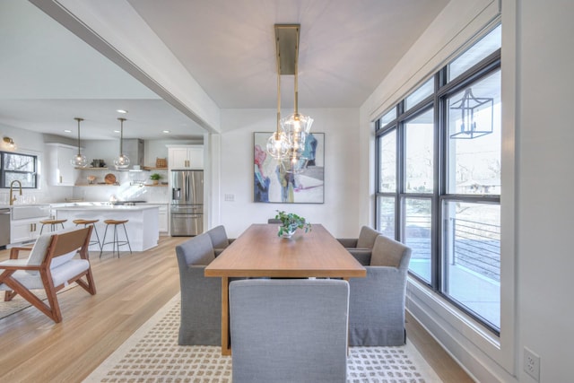 dining area with an inviting chandelier, sink, and light hardwood / wood-style floors