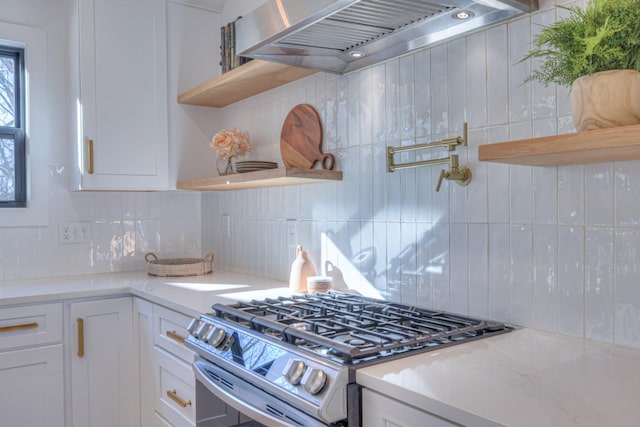 kitchen featuring stainless steel gas stove, white cabinets, and wall chimney exhaust hood