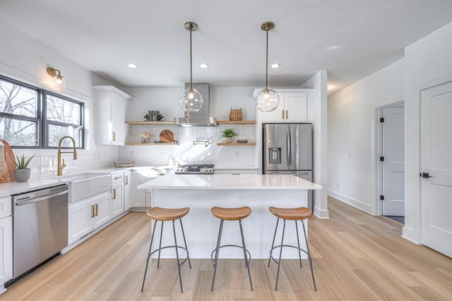 kitchen featuring white cabinets, stainless steel appliances, sink, and wall chimney range hood