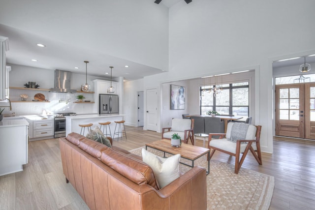 living room featuring french doors, a high ceiling, sink, and light hardwood / wood-style flooring