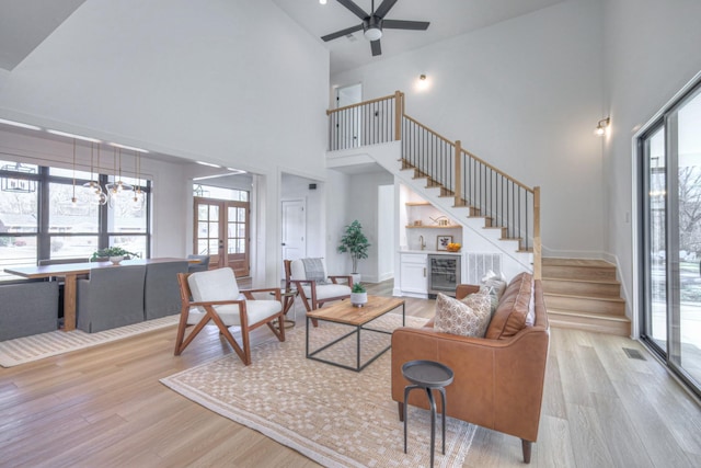 living room with indoor bar, a towering ceiling, and light wood-type flooring