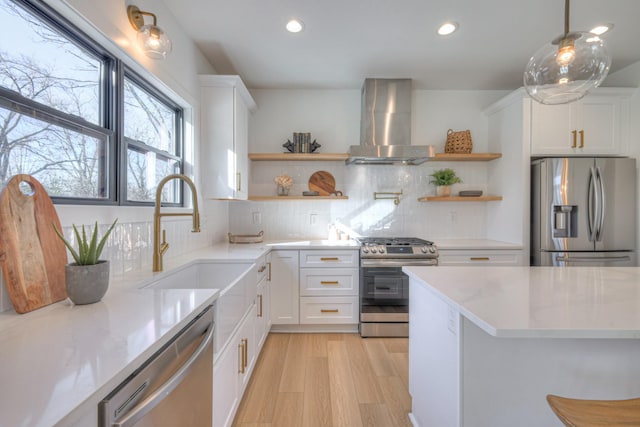 kitchen with white cabinets, hanging light fixtures, wall chimney exhaust hood, and appliances with stainless steel finishes