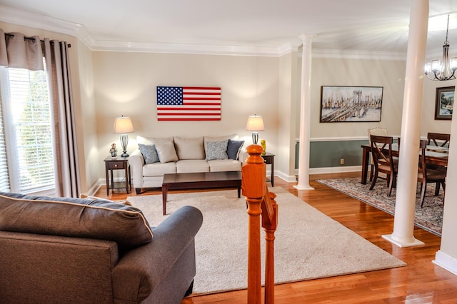 living room featuring an inviting chandelier, hardwood / wood-style flooring, ornamental molding, and decorative columns