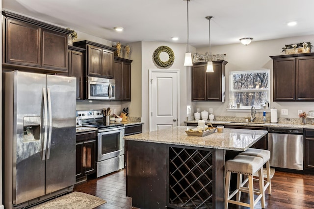 kitchen with pendant lighting, appliances with stainless steel finishes, a center island, and dark wood-type flooring