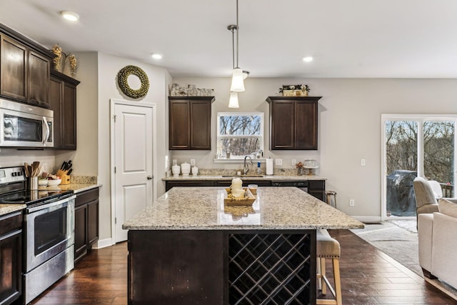 kitchen featuring dark wood-type flooring, sink, a center island, hanging light fixtures, and appliances with stainless steel finishes