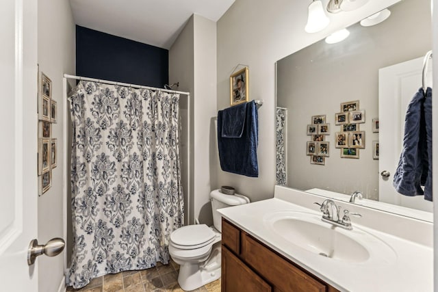 bathroom featuring vanity, walk in shower, and toilet