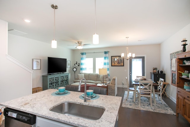 kitchen featuring pendant lighting, sink, dishwasher, light stone countertops, and an island with sink