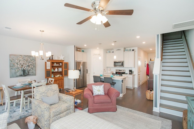 living room with ceiling fan with notable chandelier, dark hardwood / wood-style floors, and sink