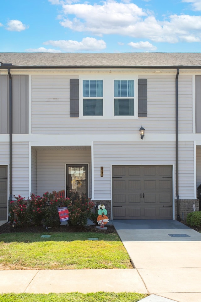 townhome / multi-family property with a garage and a front lawn