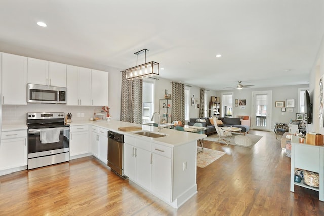 kitchen featuring appliances with stainless steel finishes, pendant lighting, white cabinets, and kitchen peninsula