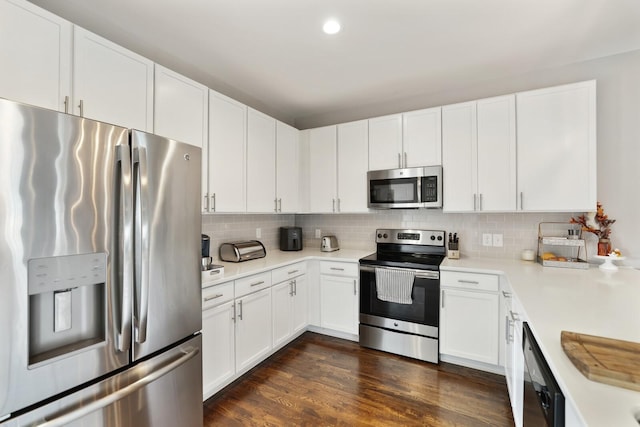 kitchen with tasteful backsplash, appliances with stainless steel finishes, dark wood-type flooring, and white cabinets