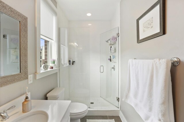 bathroom featuring a shower with door, vanity, tile patterned floors, and toilet