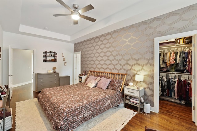 bedroom featuring dark hardwood / wood-style flooring, ceiling fan, a closet, and a raised ceiling