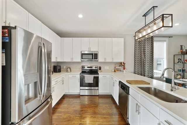 kitchen with sink, white cabinetry, decorative light fixtures, stainless steel appliances, and decorative backsplash