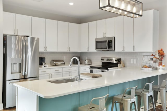 kitchen with sink, a breakfast bar area, white cabinetry, tasteful backsplash, and stainless steel appliances